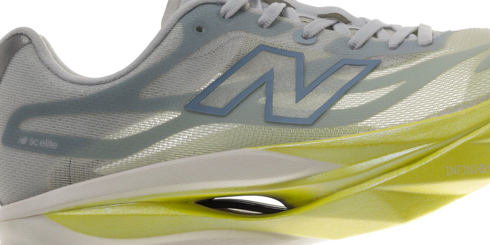 Close-up side view of a New Balance running shoe featuring a light gray mesh upper, blue &ldquo;N&rdquo; logo, white laces, and a lime-green sculpted midsole with a visible hollow cushioning design.